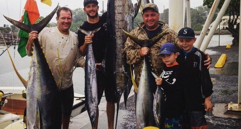 Marlin sport fishermen showing off their catch on the docks on the North Shore. Mahi-mahi and yellowfin tuna are also displayed.